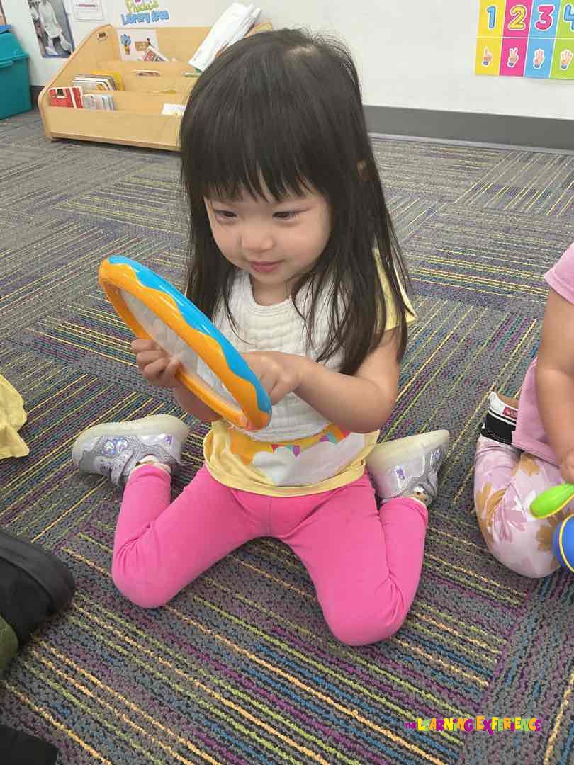 Child playing with a bright orange and blue toy