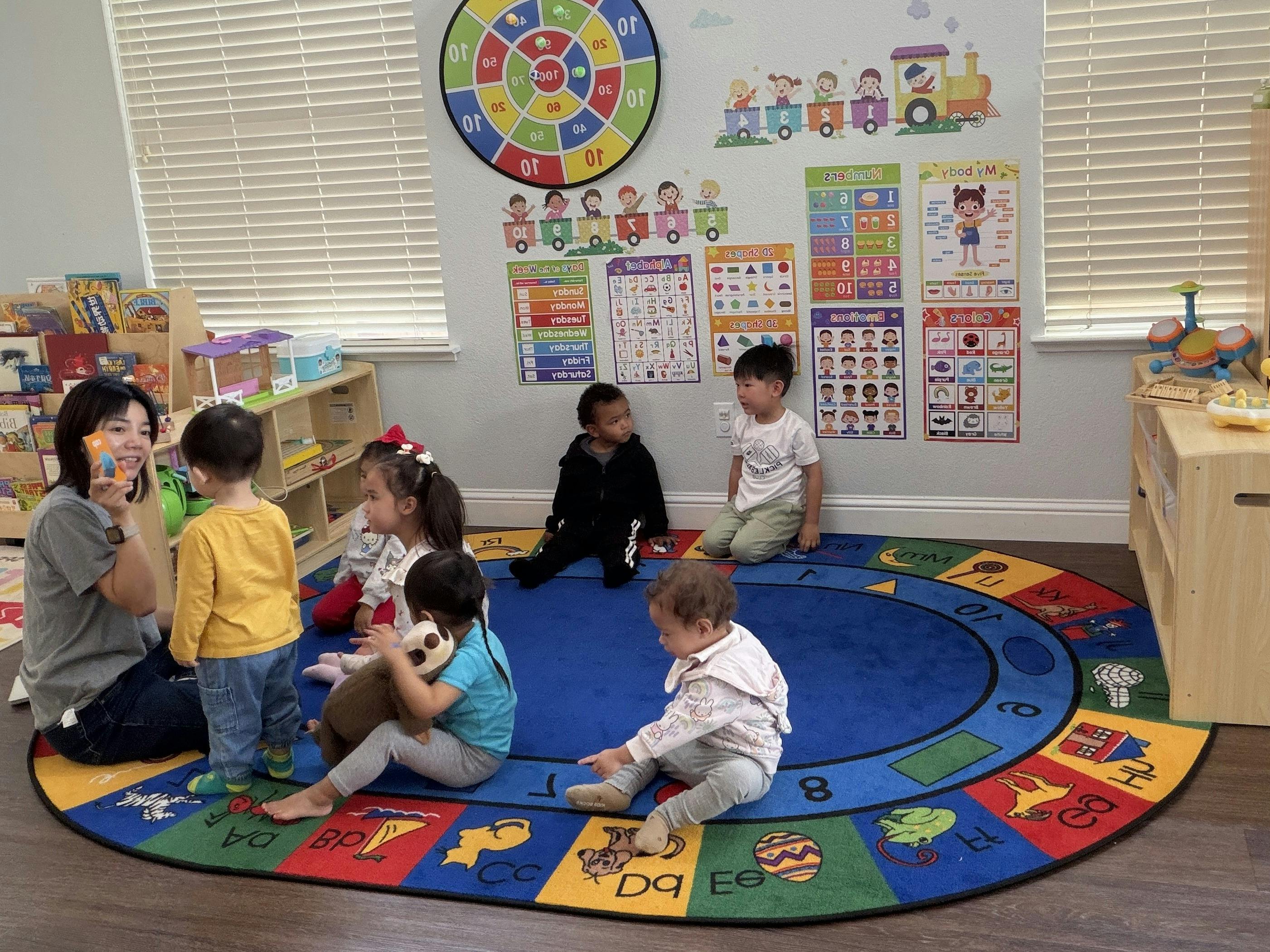 A teacher leading a group of children sitting on a circular classroom rug