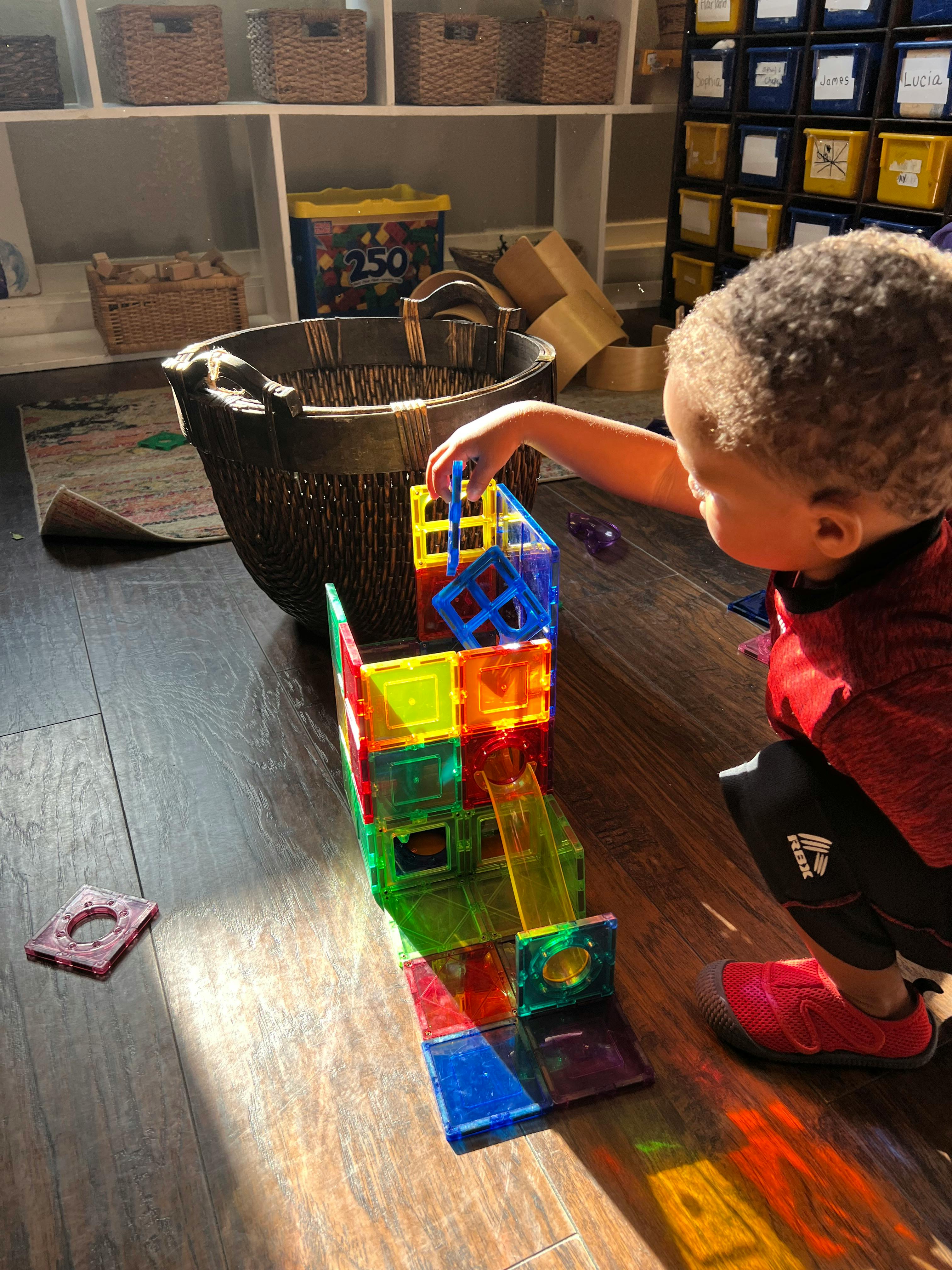 Child playing with colorful magnetic building blocks on a wooden floor