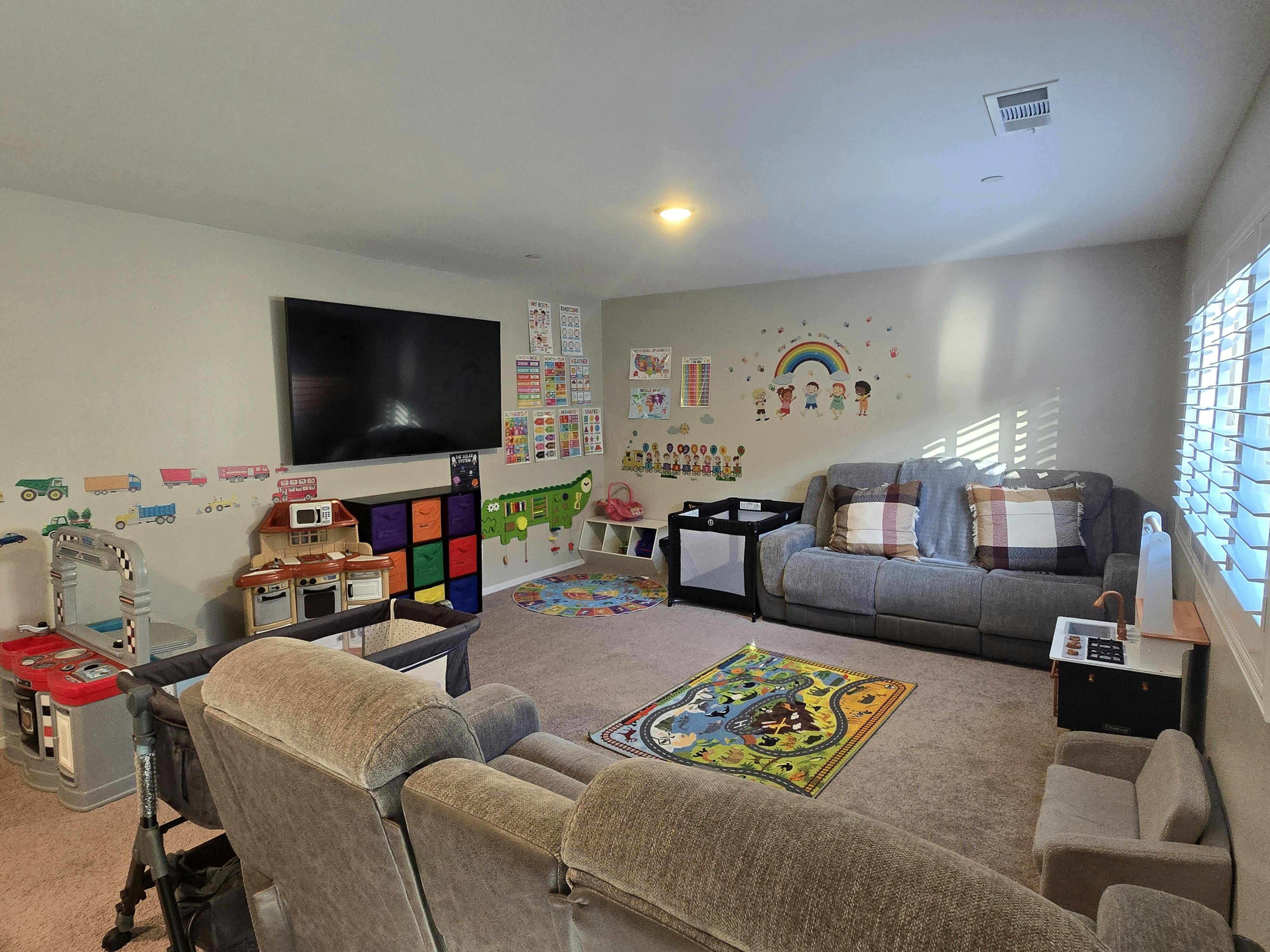 Living room with a television, sofa, and children's play area