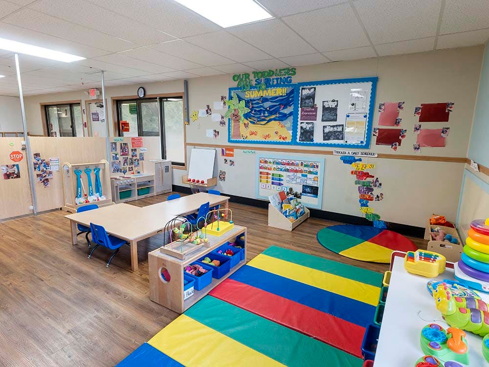 Classroom with child-sized tables, chairs, toys, and colorful mats
