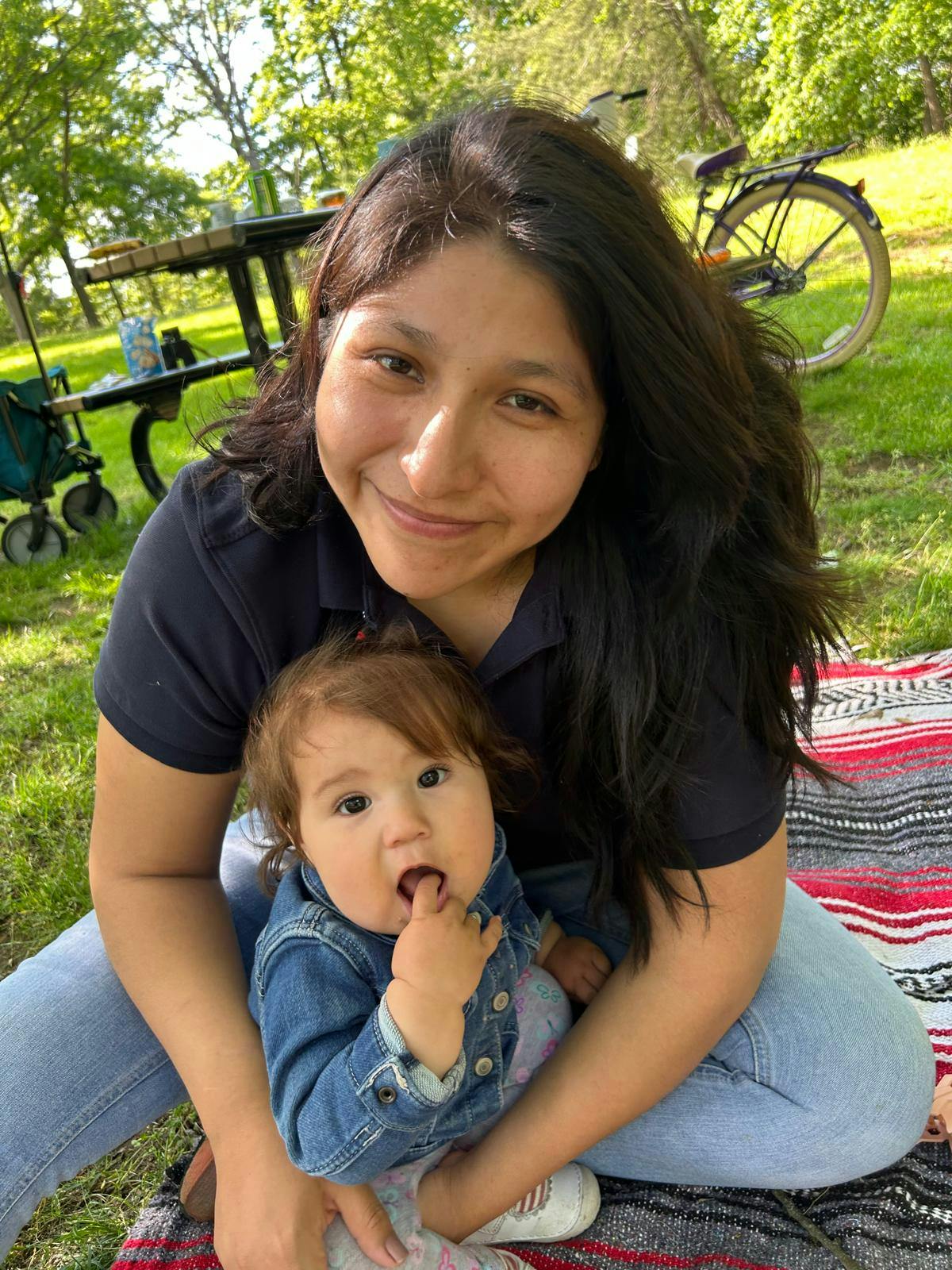 Person holding a child on a blanket in a park