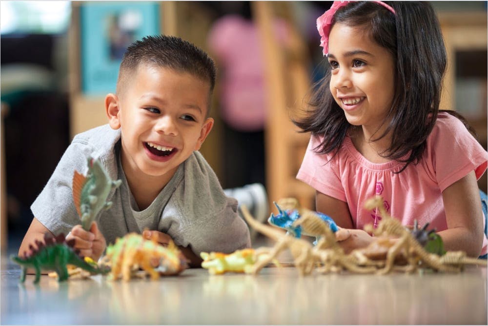 Two children playing with toy dinosaurs