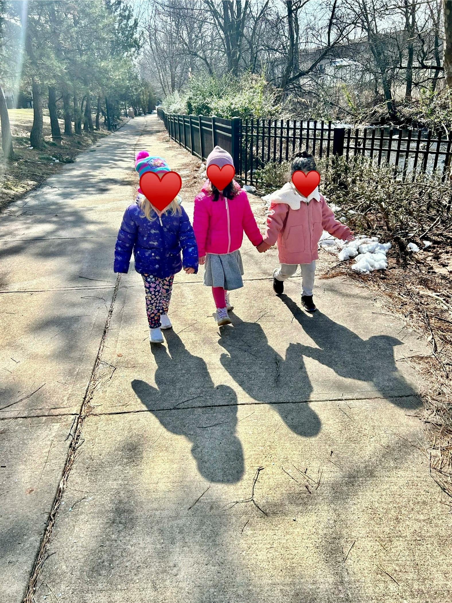 Three children walking on a sidewalk holding hands