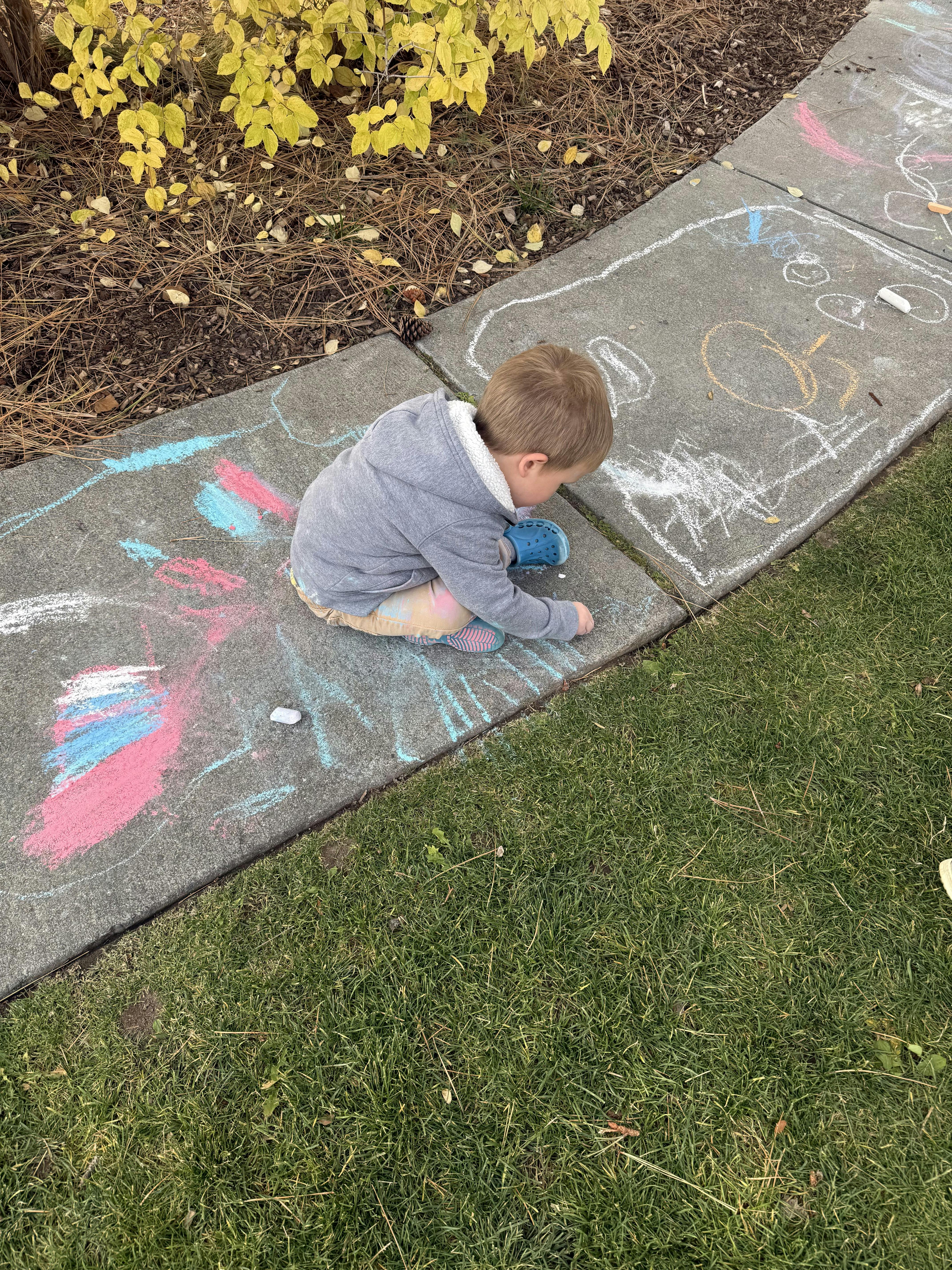 Child drawing on a concrete path with chalk