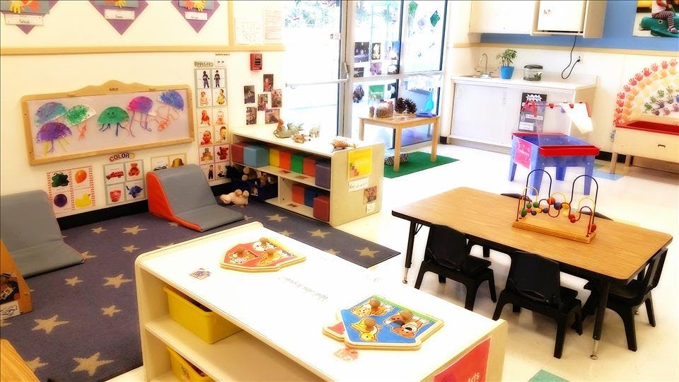 Colorful classroom with play areas, tables, chairs, and educational materials