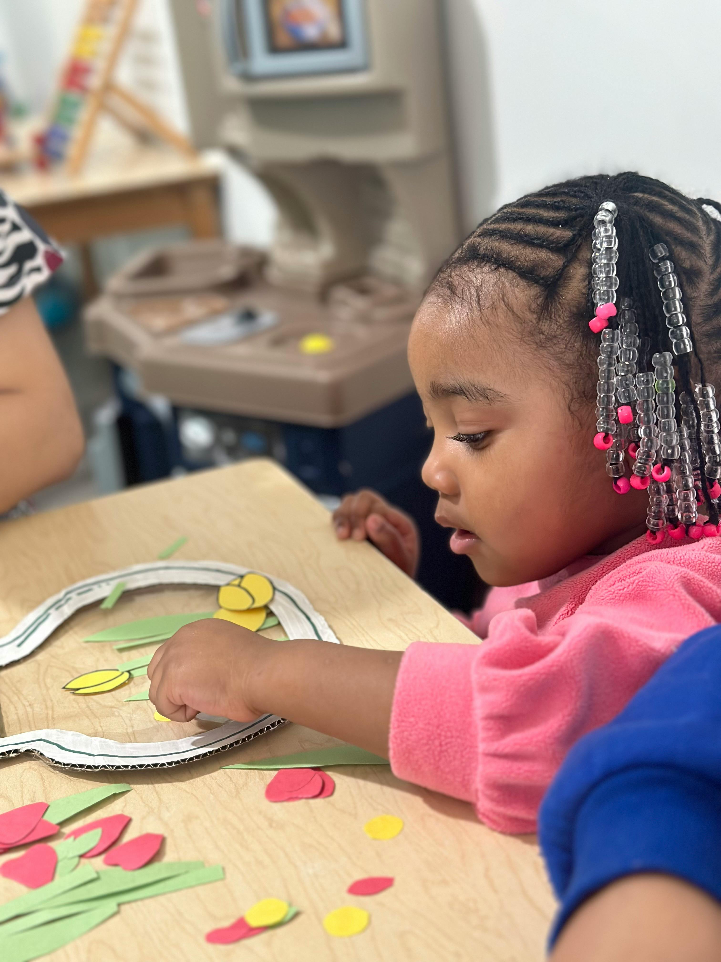 Child doing a craft with paper cutouts on a table