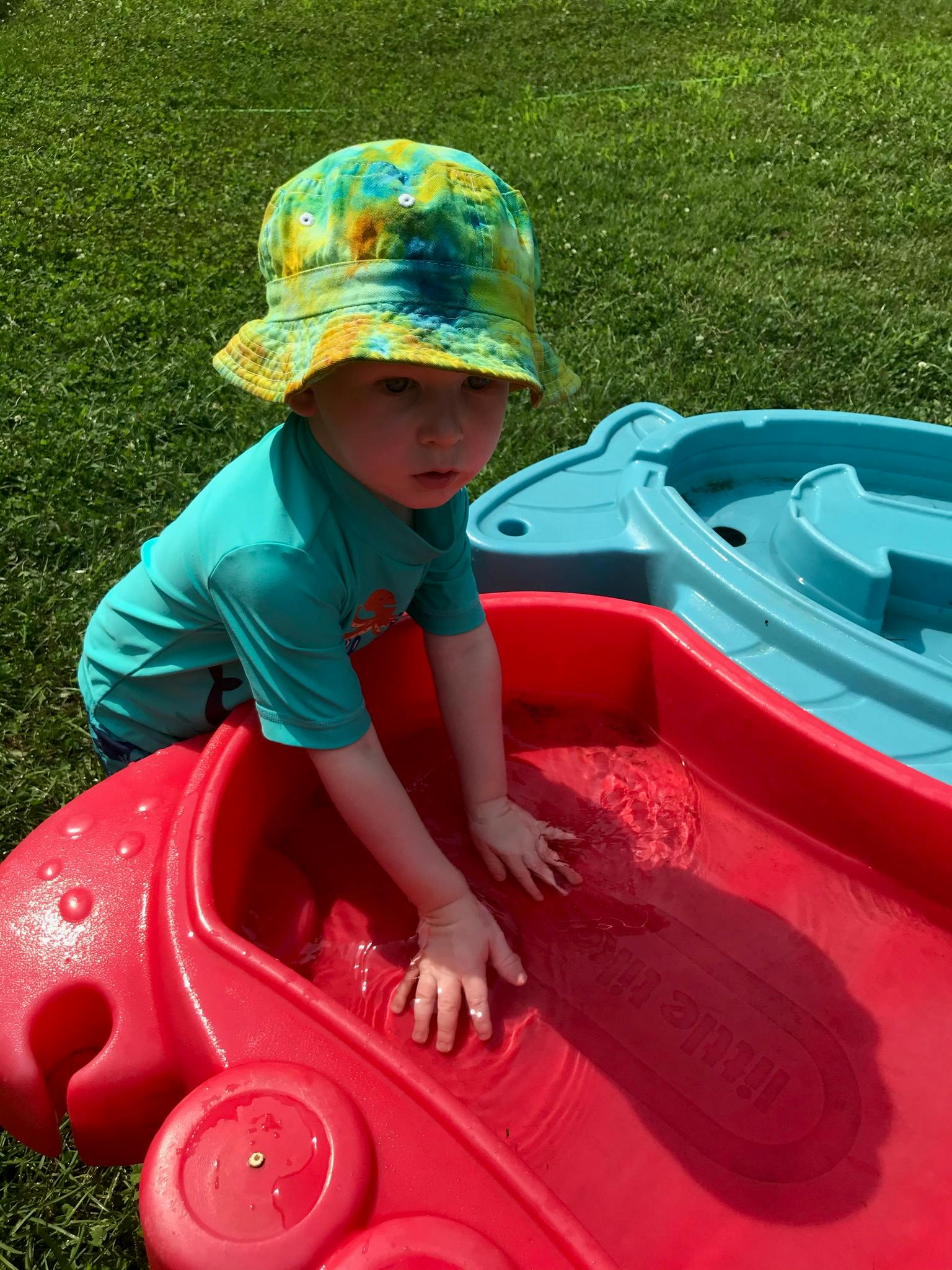 Child in a hat playing in a red water table