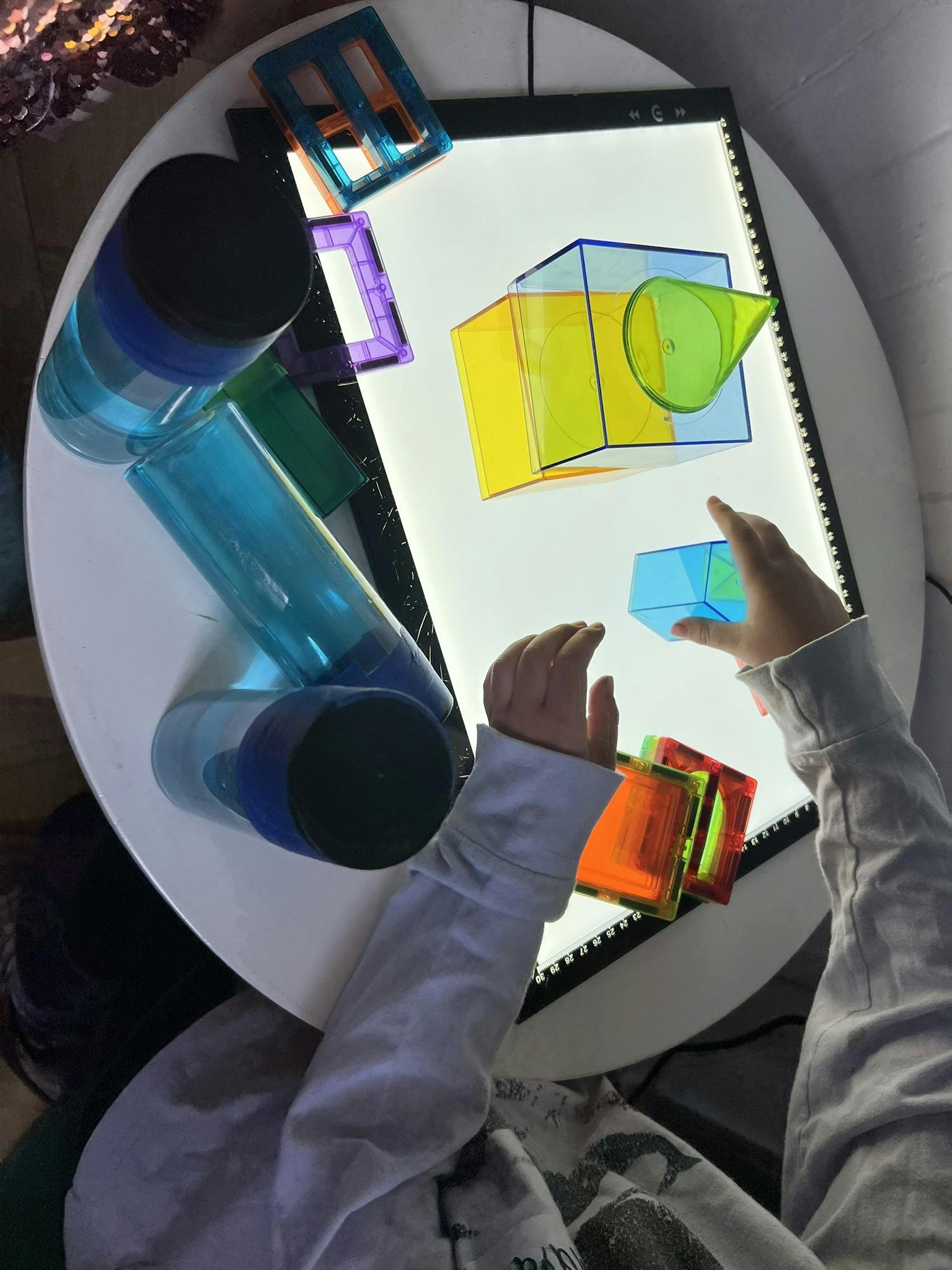 Child's hands playing with translucent blocks on a light board