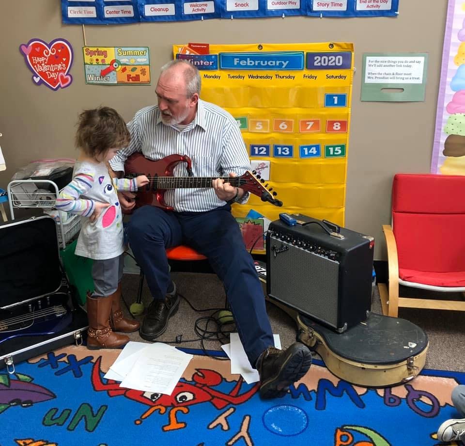 Adult playing electric guitar with a child