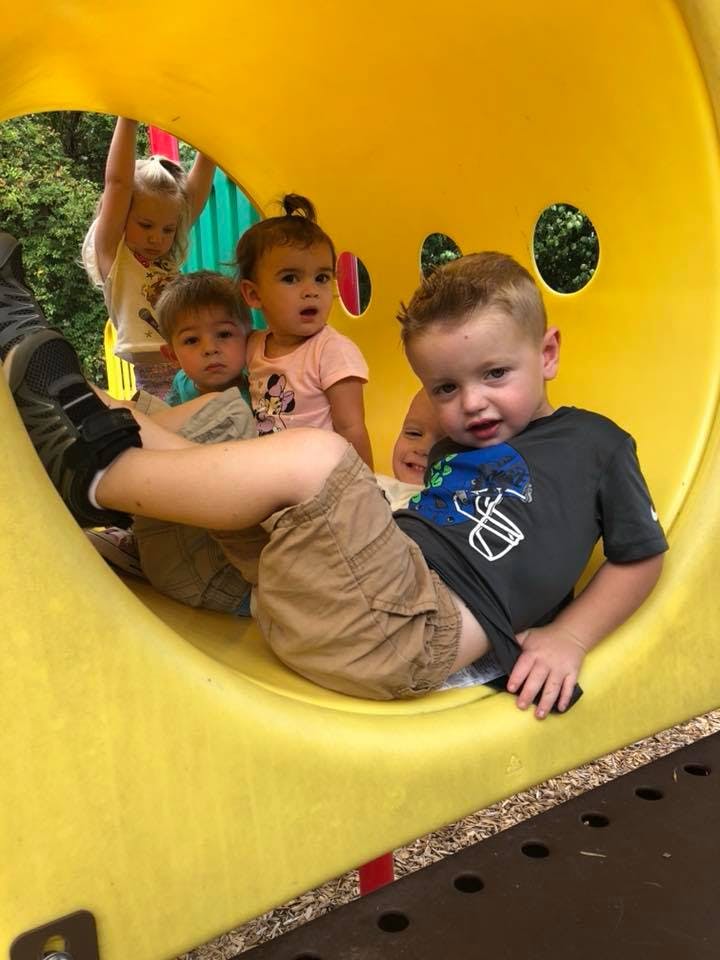 Children playing inside a yellow tunnel on a playground