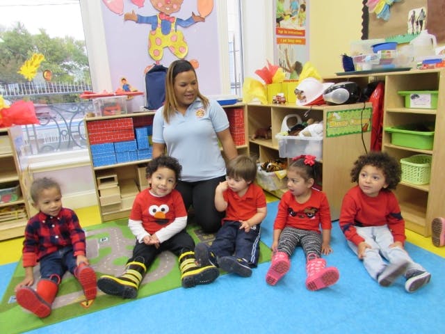 Adult and multiple children sitting on the floor in a classroom