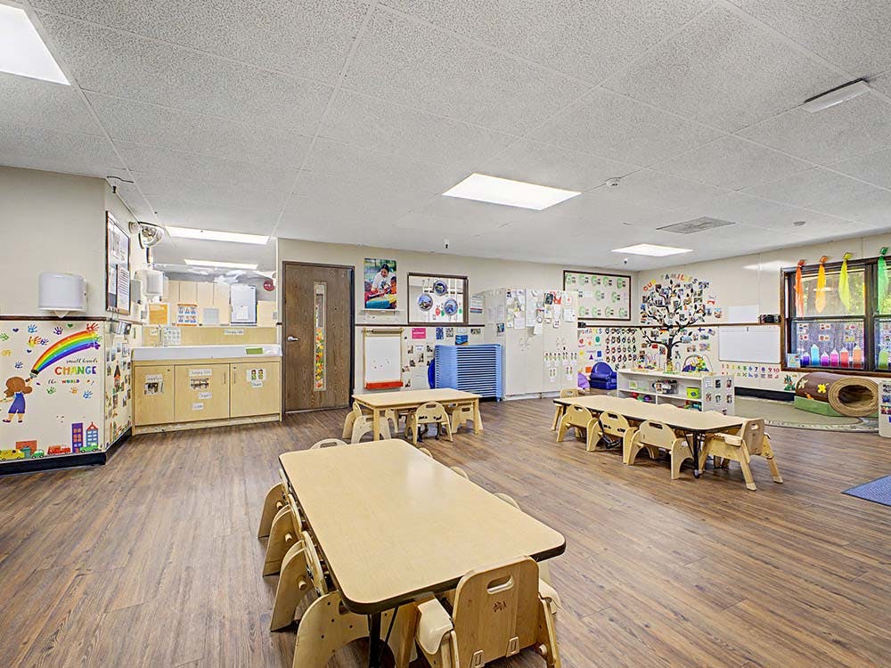 Empty classroom with small tables and chairs, and colorful decorations