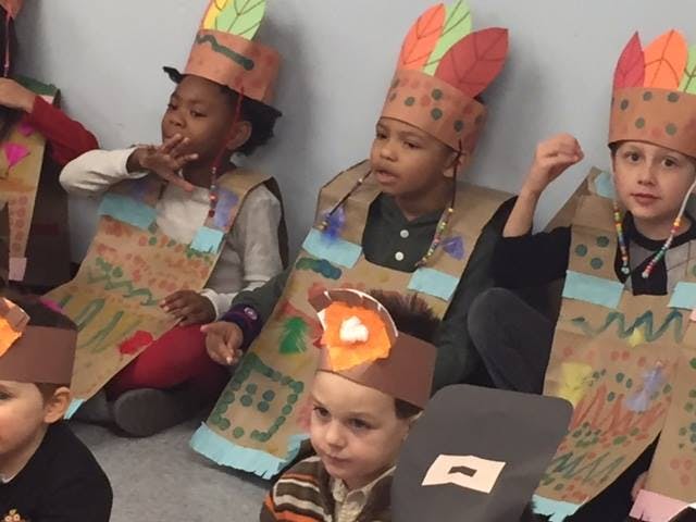 Children in paper costumes with feather headbands
