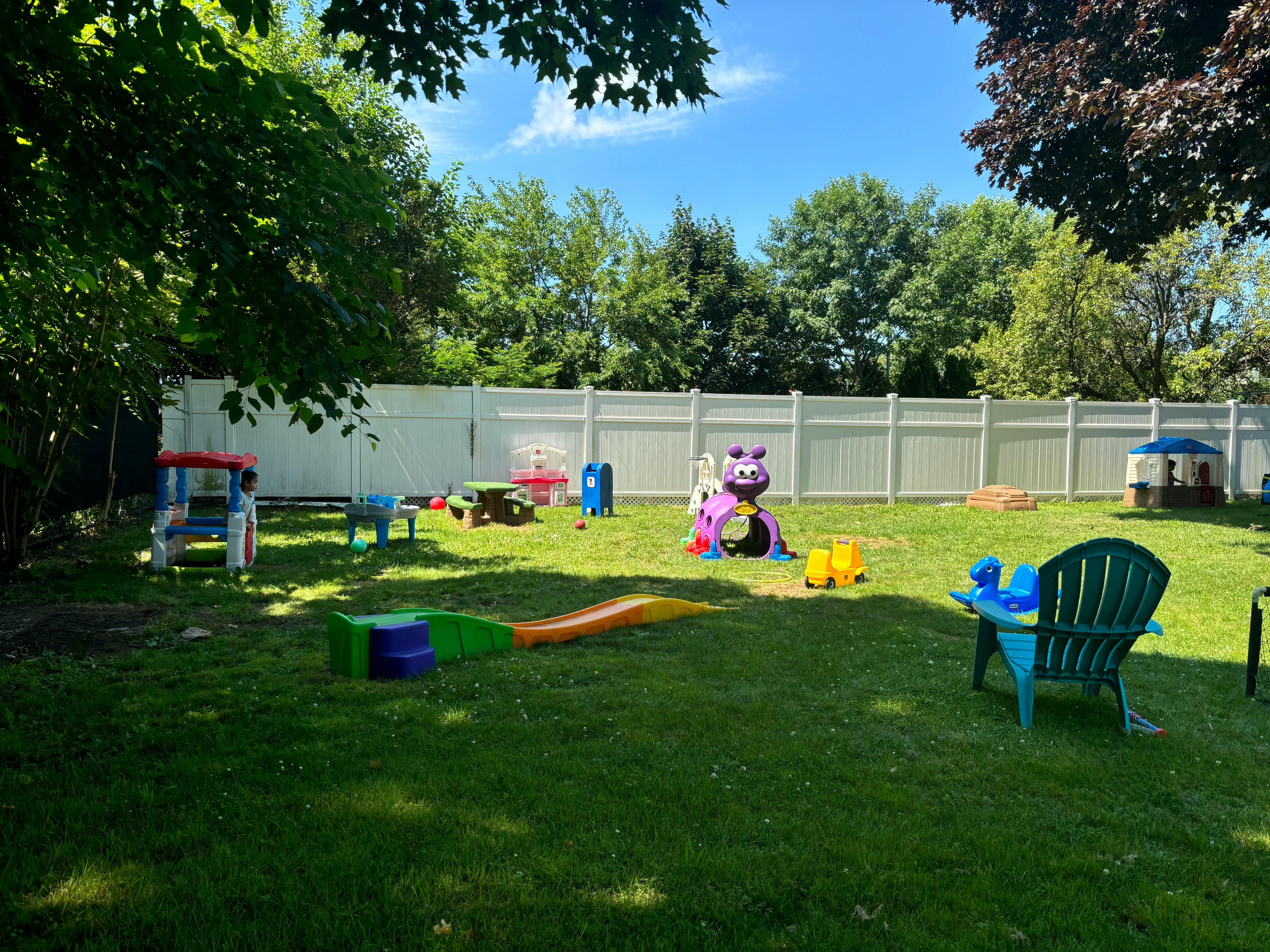 Backyard with a white fence and various colorful children's play equipment