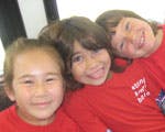Three children in red shirts looking at the camera