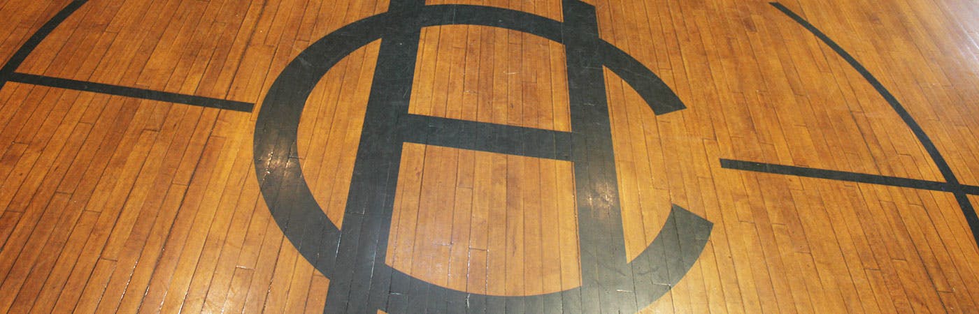 Basketball court floor with painted black lines and a large "HC"