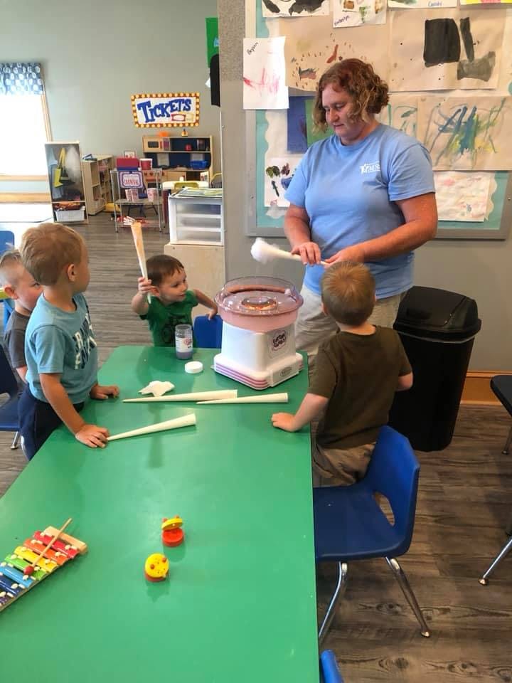 Adult and children making cotton candy in a classroom