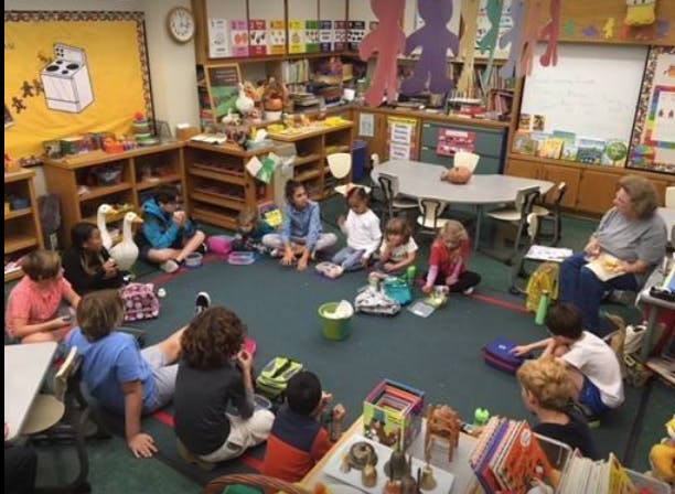 Children and an adult sitting in a circle in a classroom