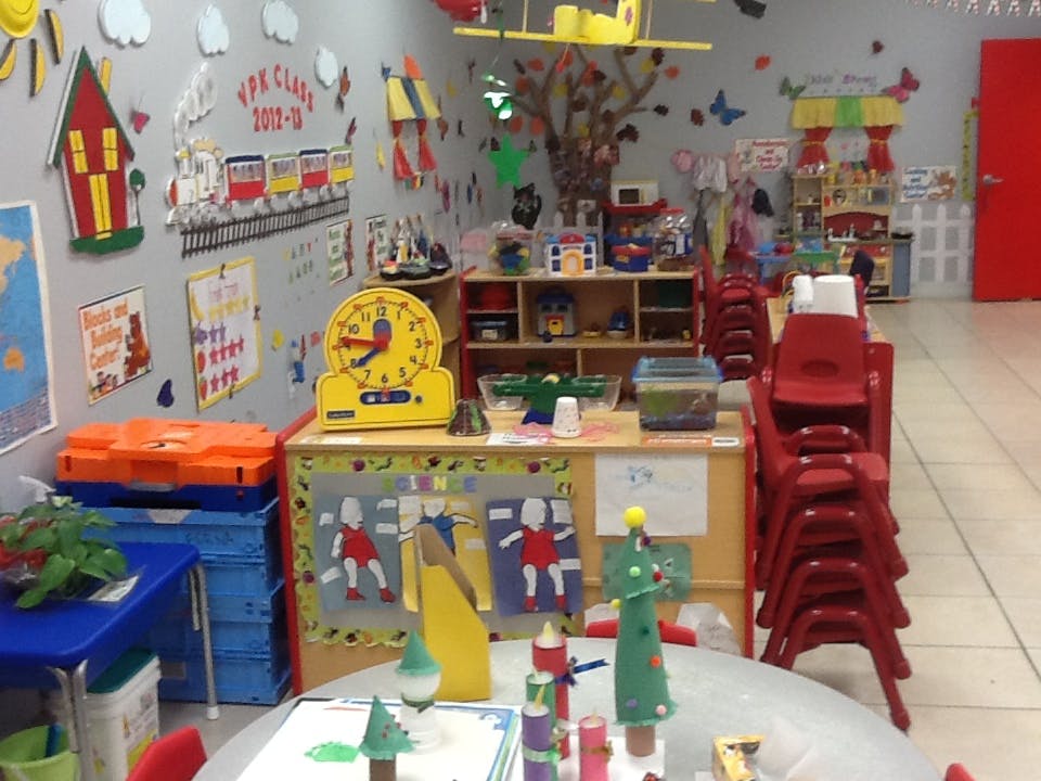 Classroom with colorful decorations, tables, and stacked red chairs