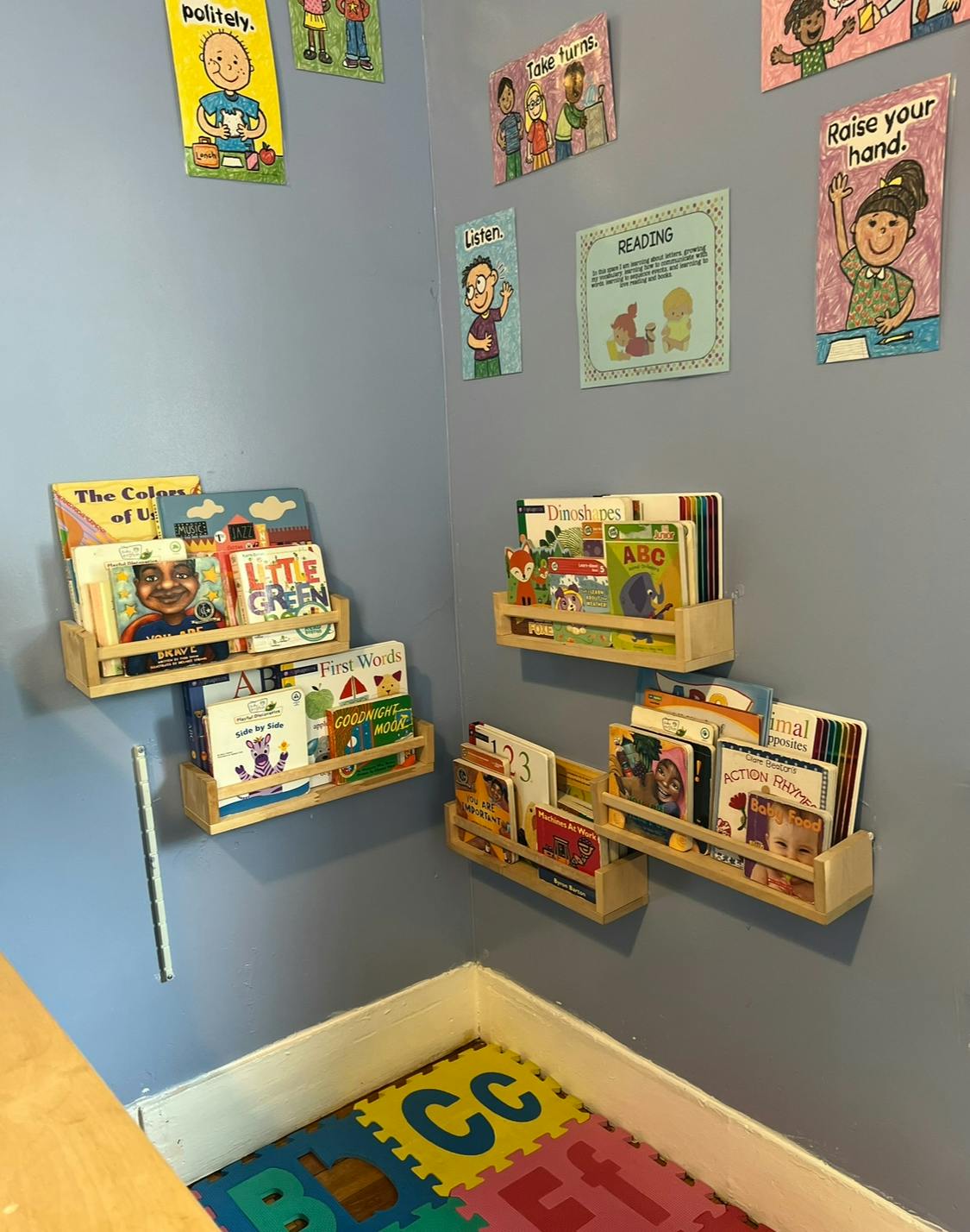 Wall-mounted bookshelves filled with children's books above a play mat