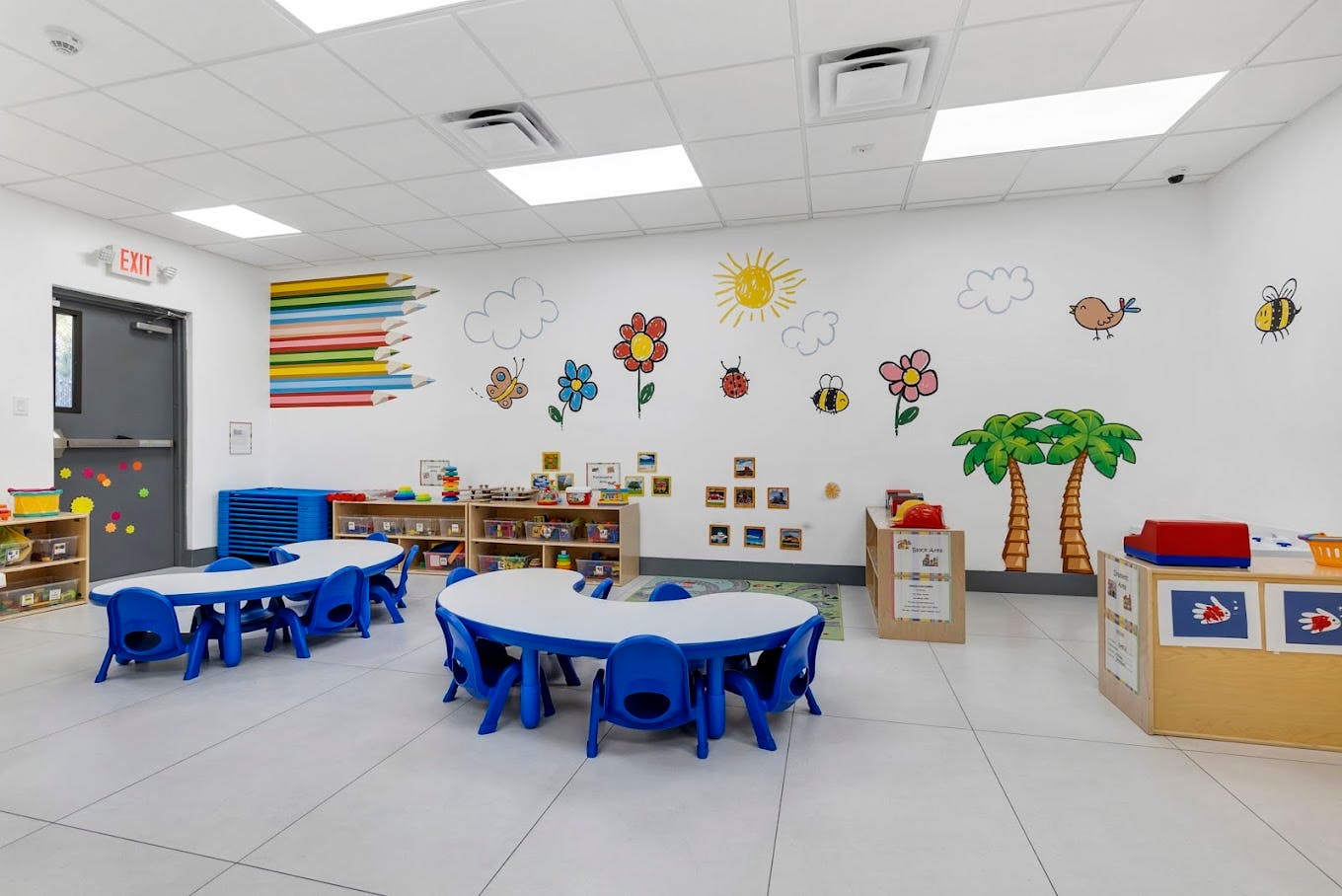 Classroom with small blue tables and chairs, colorful wall decorations