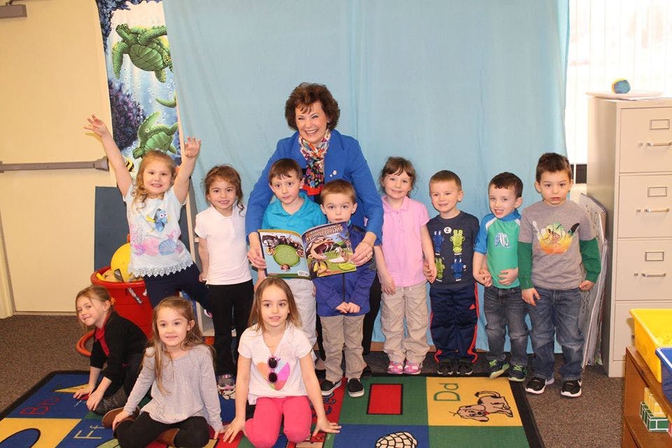 Adult and multiple children posing for a photo, some holding books