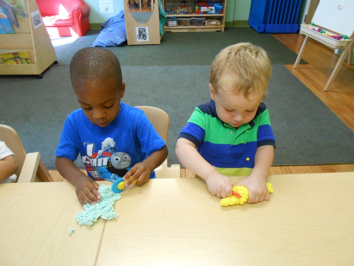 Two children playing with modeling clay at a table