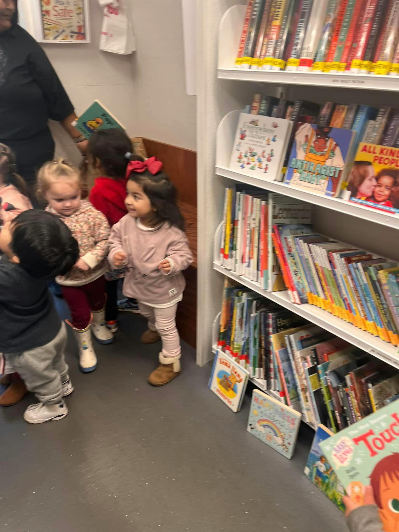 Children standing near a bookshelf in a library