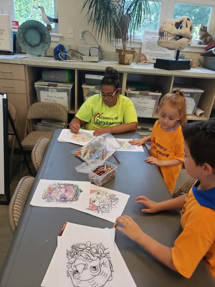 Person and two children coloring at a table