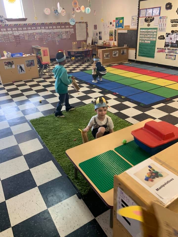 Children playing in a classroom with checkered floor and colorful mats