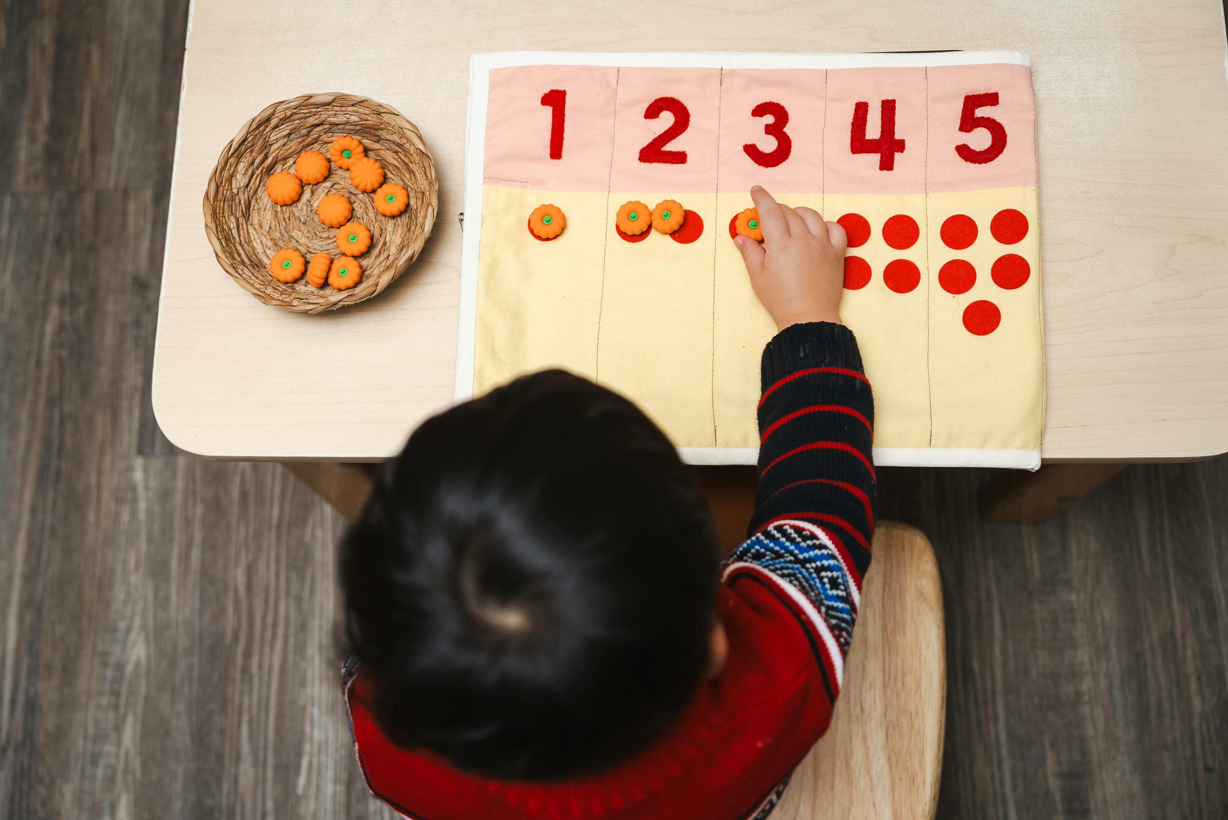 Child counting with number board and small objects
