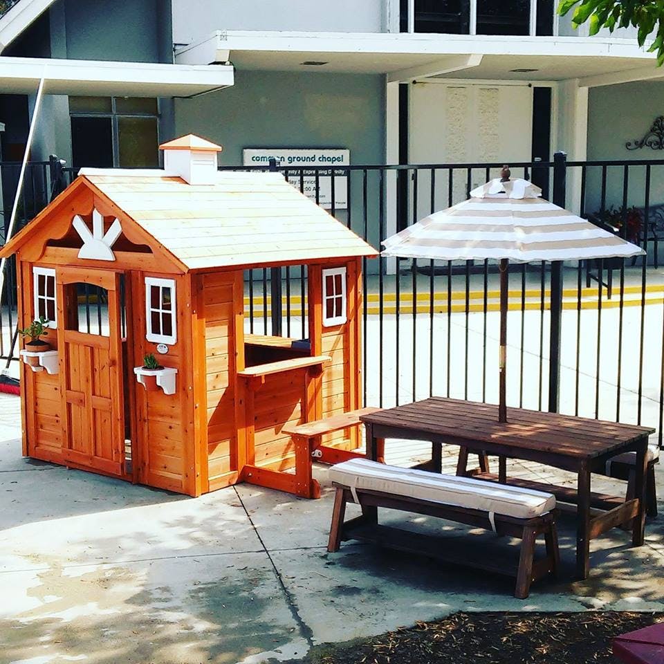 Wooden playhouse next to a picnic table with an umbrella