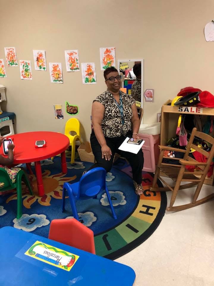 Person kneeling in a classroom with children's artwork on the wall
