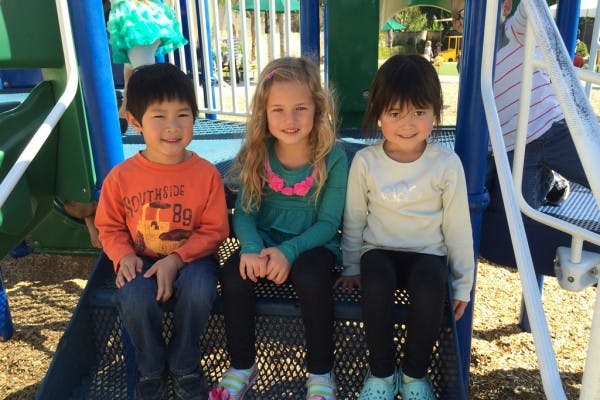 Three children sitting on playground equipment