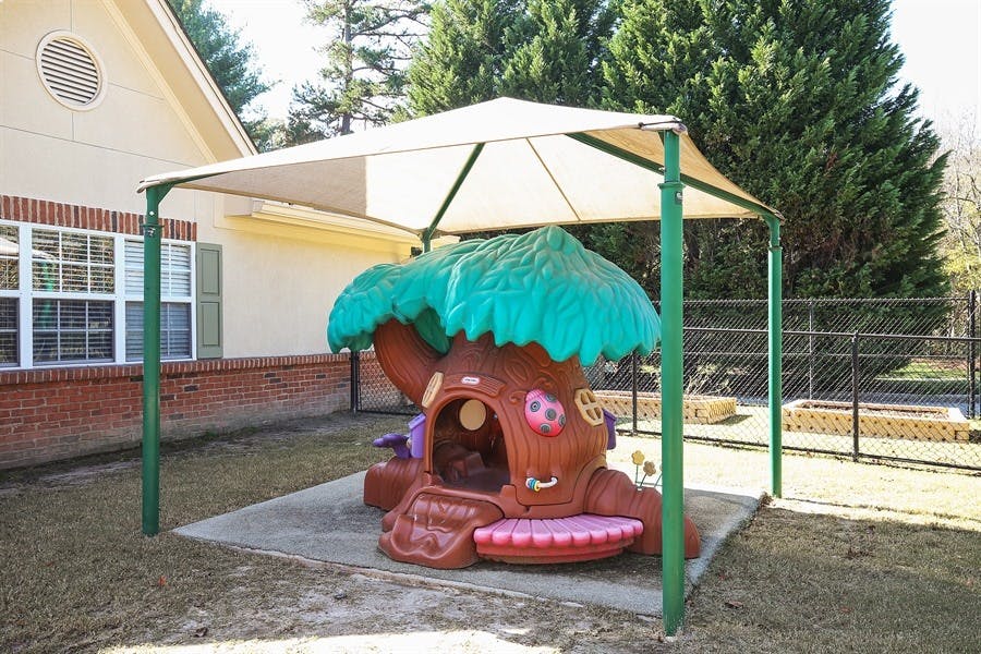 Playground with a treehouse play structure under a canopy