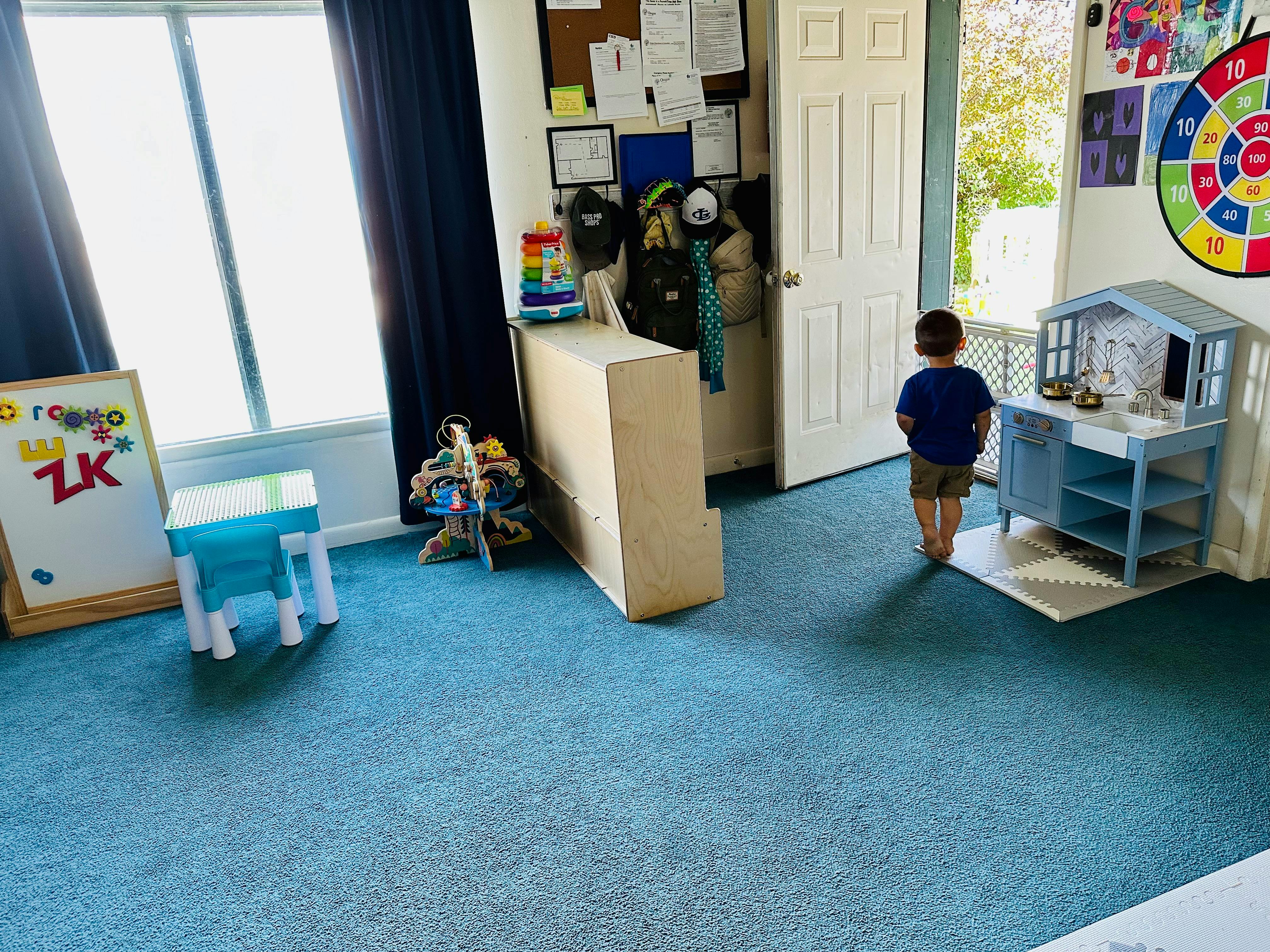 Child standing in a room with a play kitchen