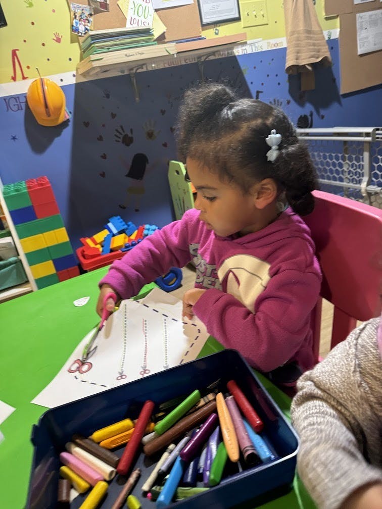 Child in a classroom cutting paper with scissors