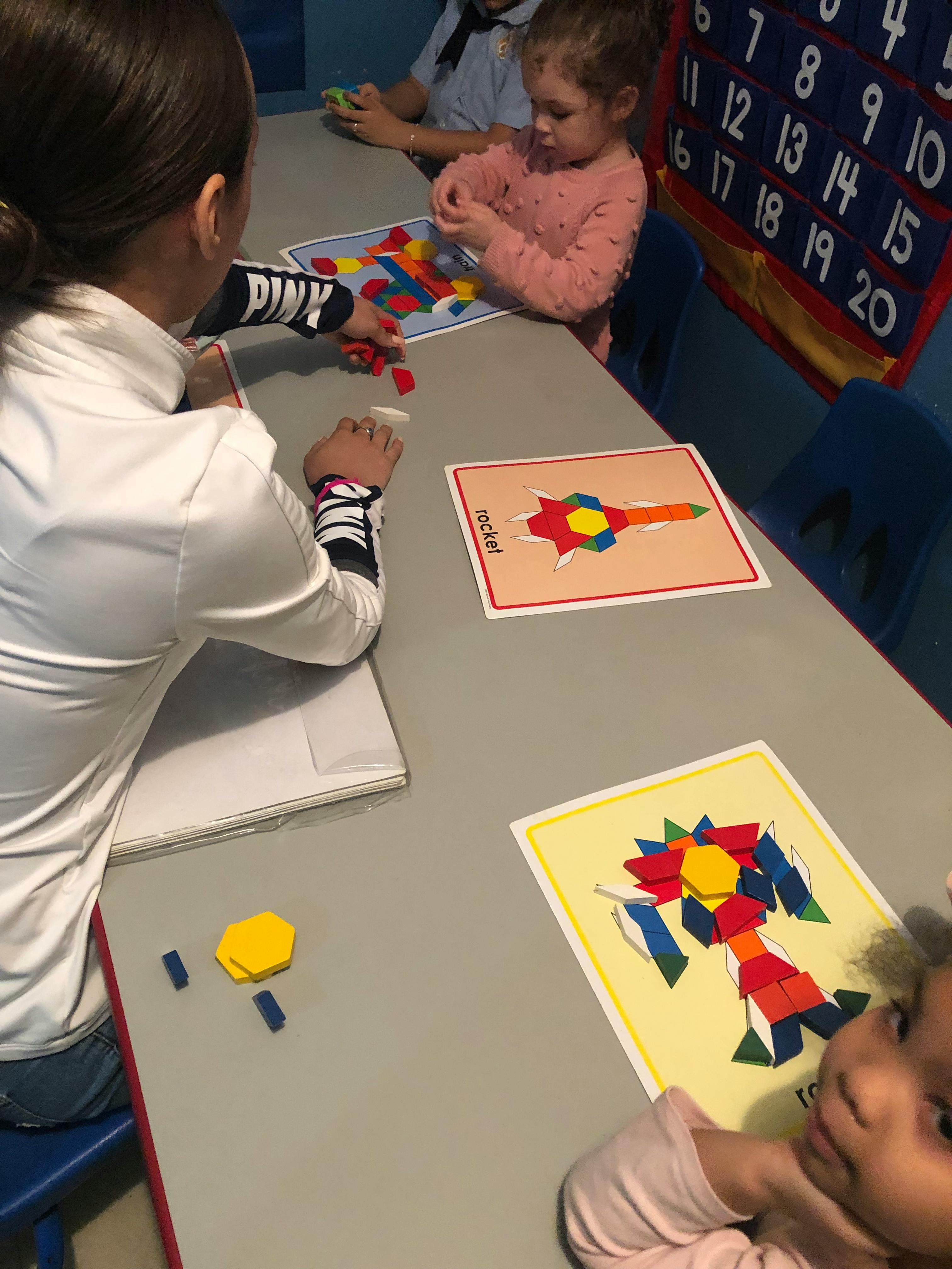 People and children playing with colorful pattern blocks at a table