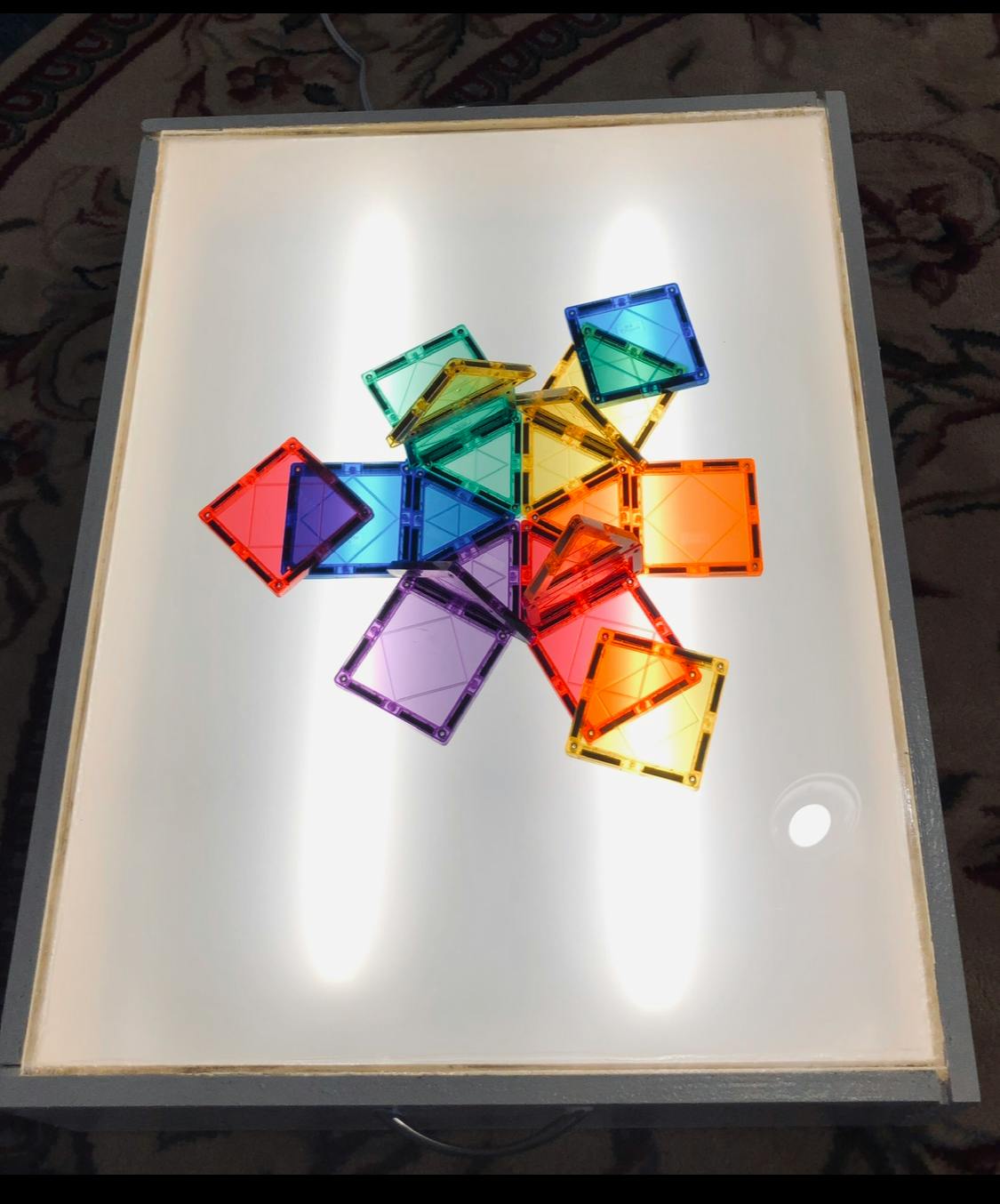 Colorful translucent magnetic tiles arranged on a light table