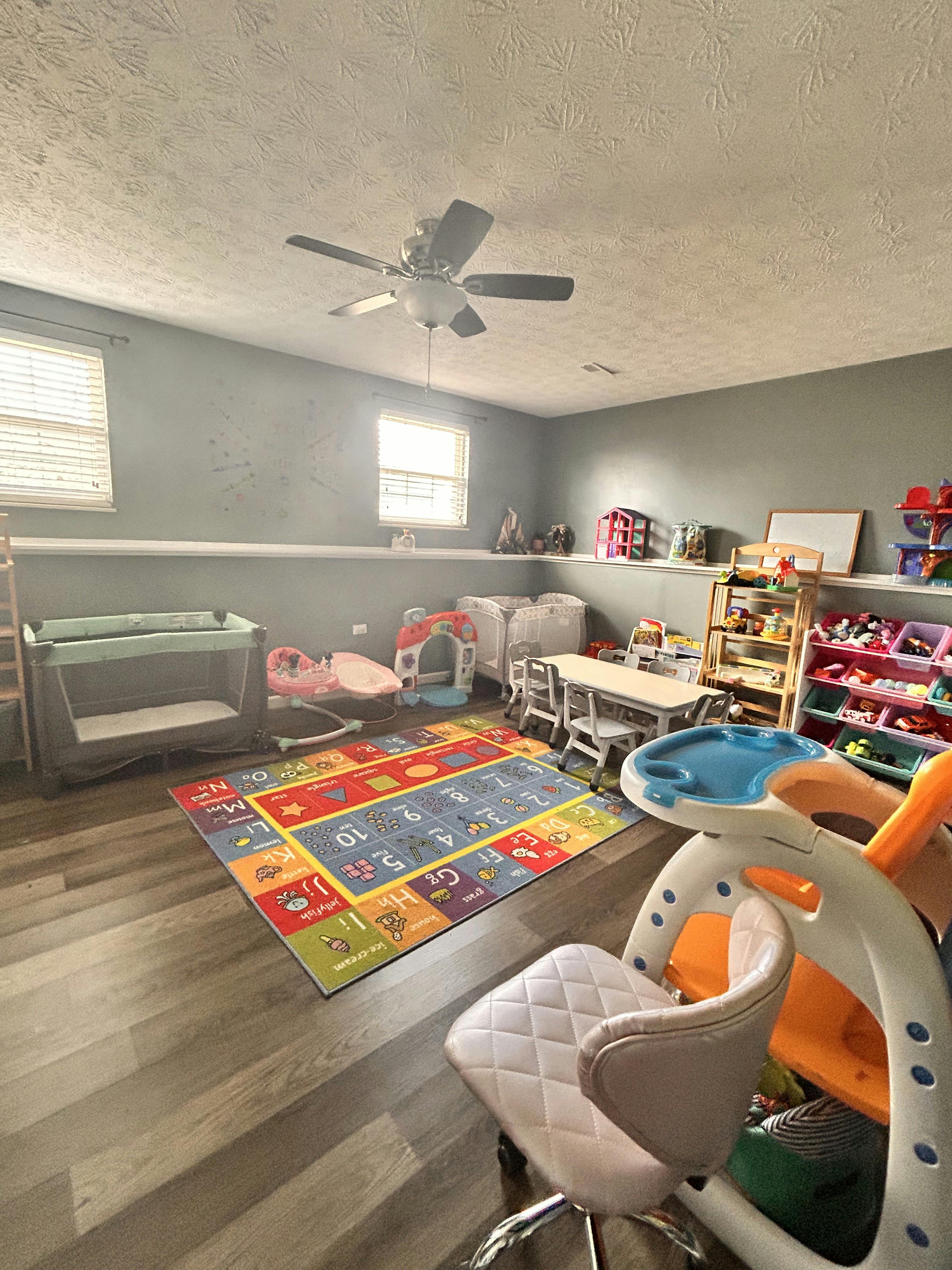 Playroom with a colorful alphabet rug, small table and chairs, and toys