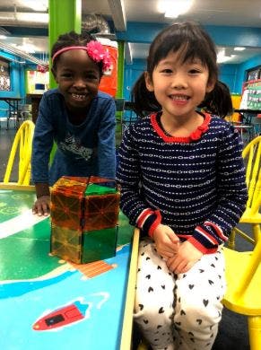 Two children smiling at a table with a toy boat and a boat drawing