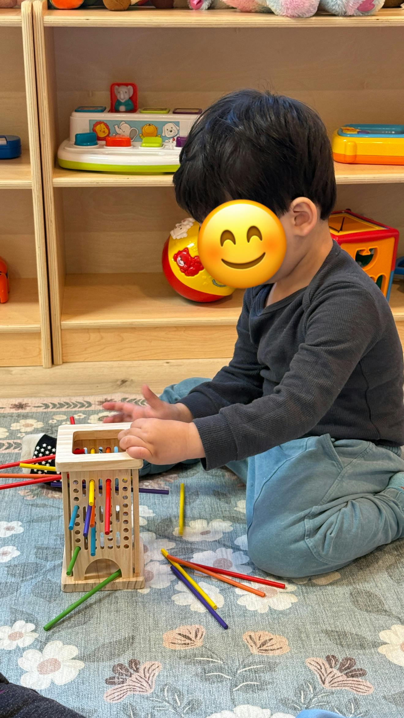 Child playing with a wooden stick game on a rug