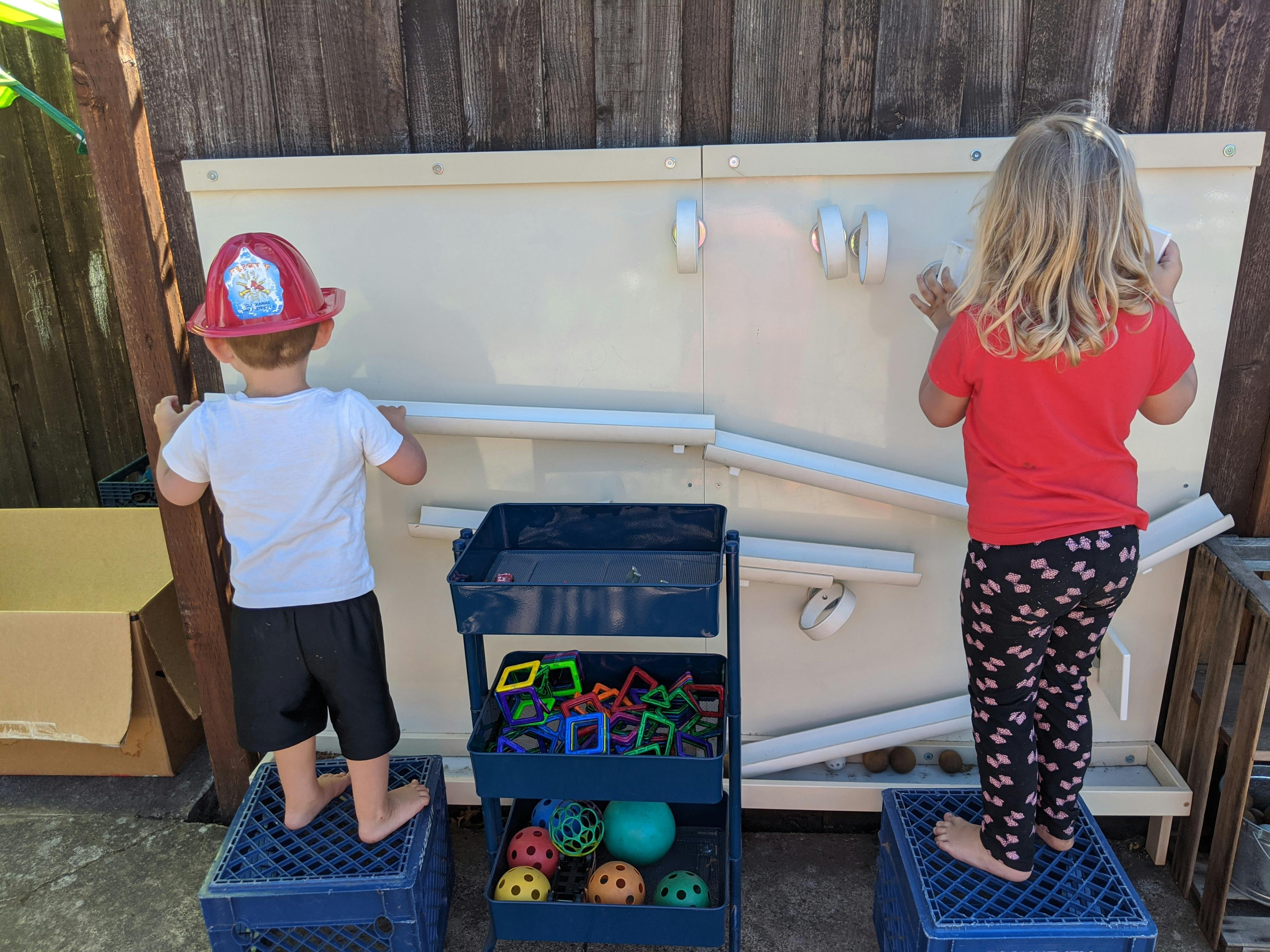 Two children playing with a water wall