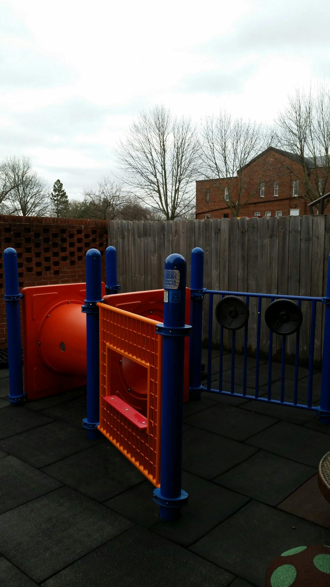 Playground equipment with red and blue structures on dark rubber tiles