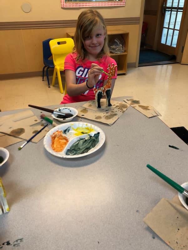 Child painting a figurine at a table