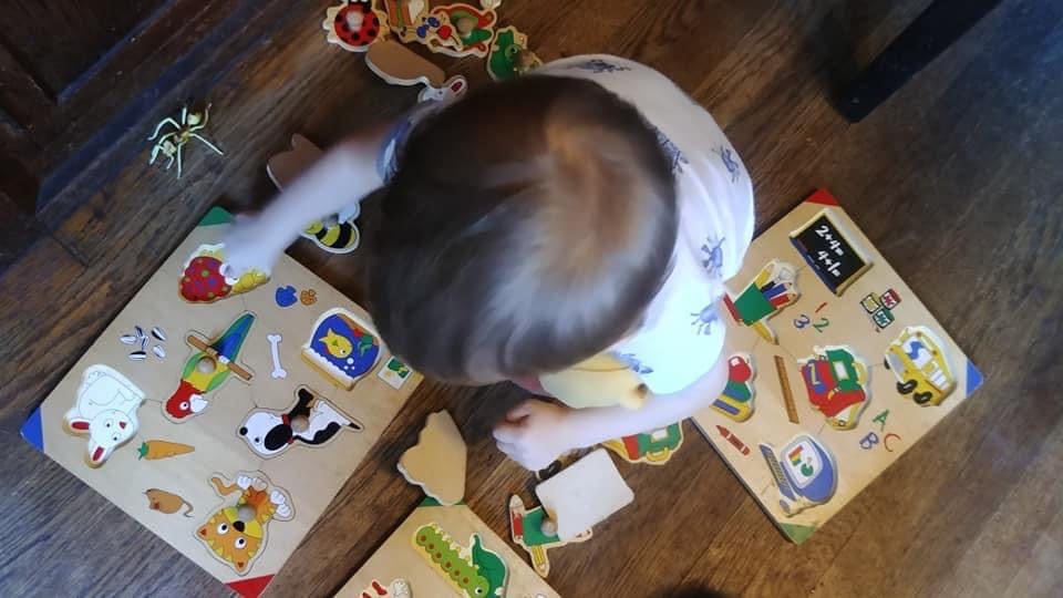 Child playing with wooden puzzles on a floor