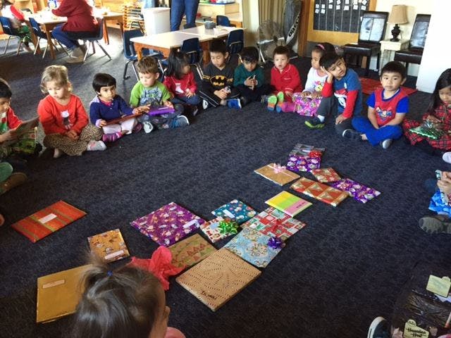 Children sitting in a circle on the floor with wrapped gifts in the center
