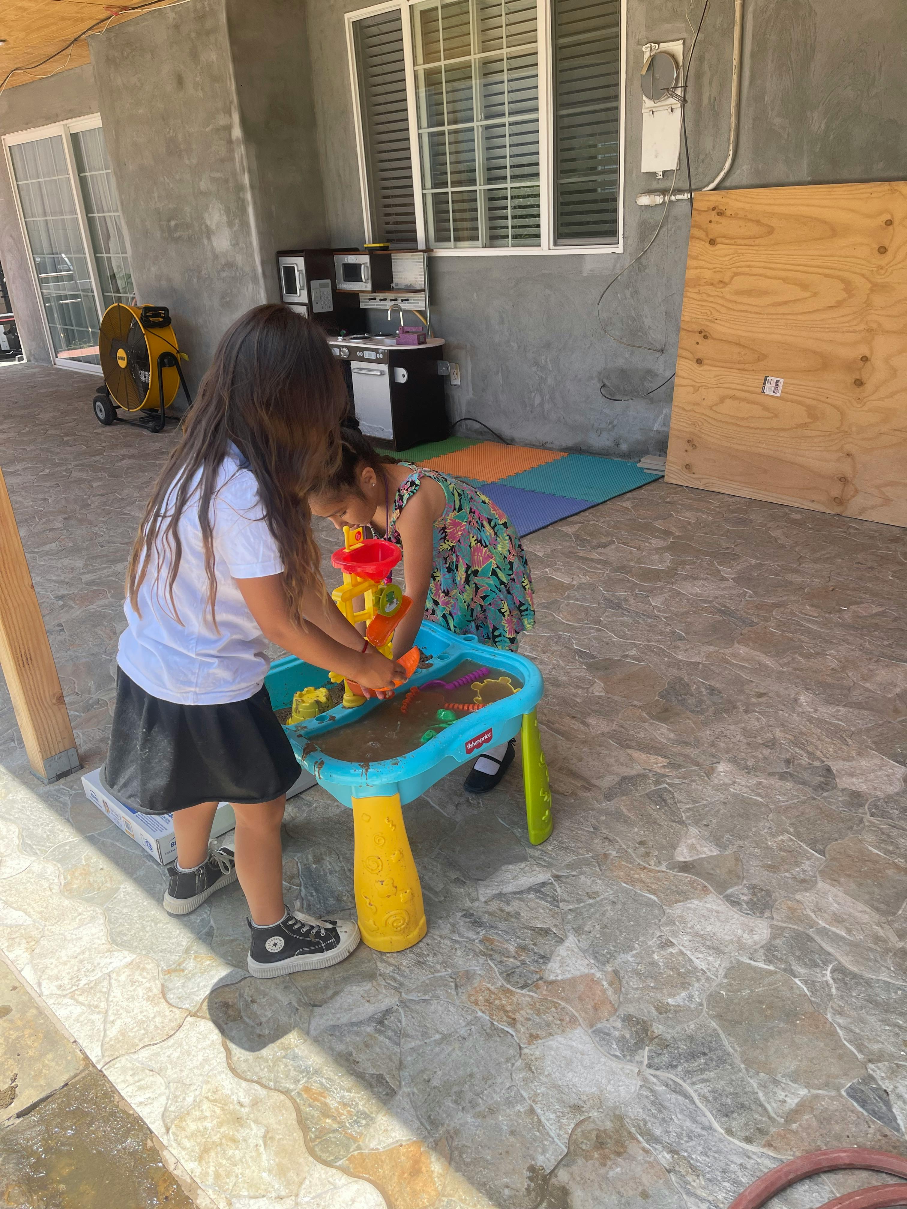Two children playing with a sand and water table