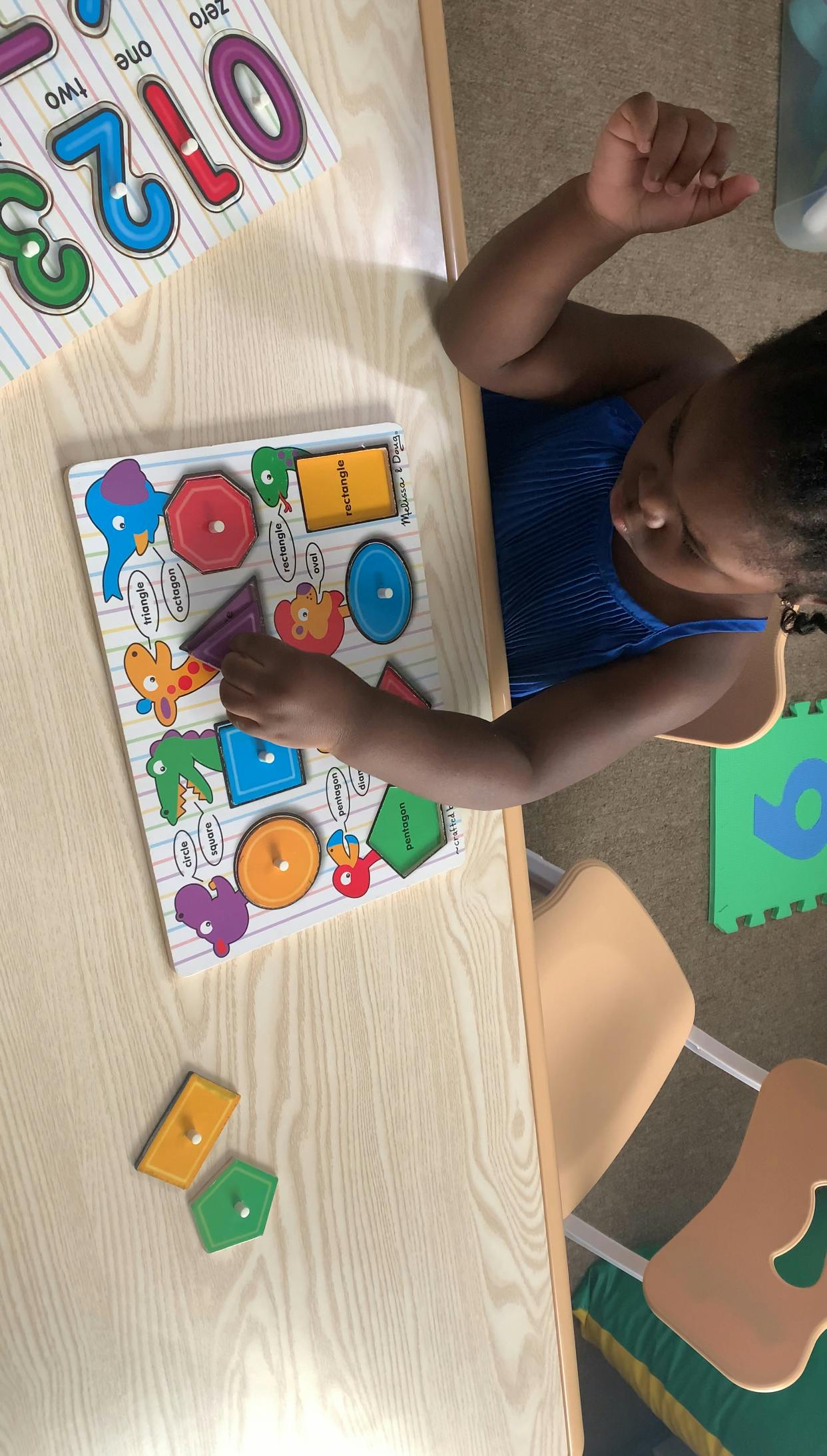 Child playing with a shape puzzle on a wooden table